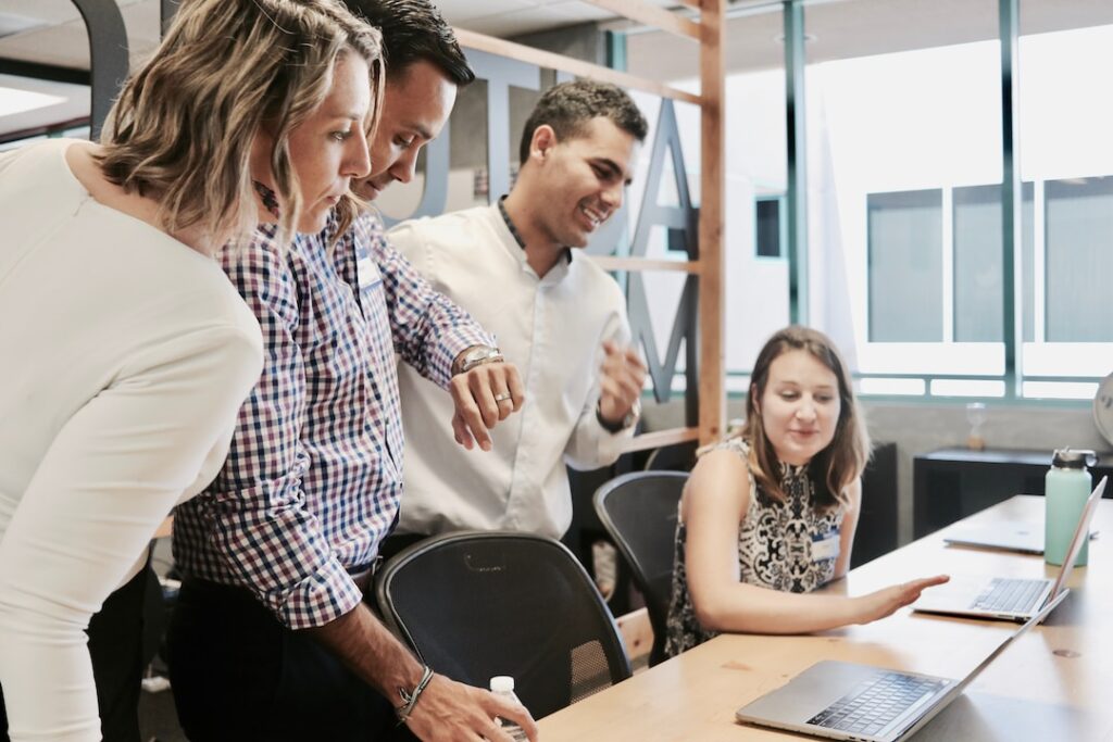 Four people looking at a laptop screen discussing implementing account planning strategies