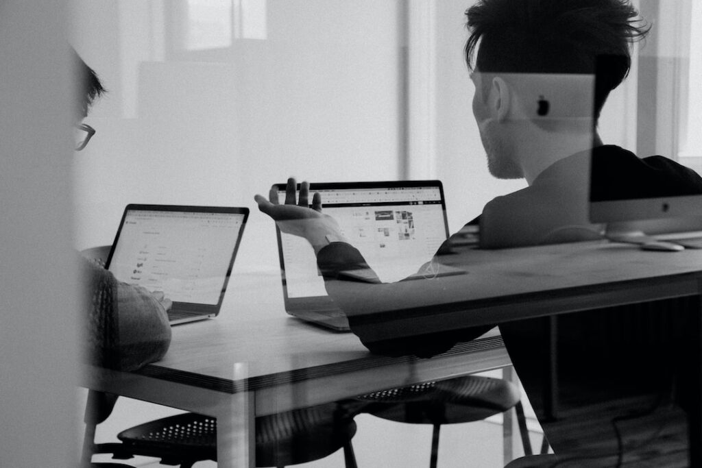 Two people sitting at a table with laptops discussing implementing account planning strategies